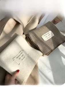 Détail de l'écharpe en maille blanc crème et marron foncé au motif à chevrons