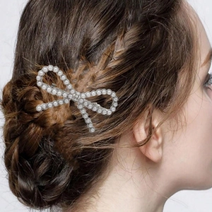 Detailed view of elegant silver bow hair clip with white pearls on model's updo hairstyle