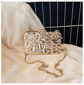 Detail of metallic gold evening clutch with lava texture and golden chain strap