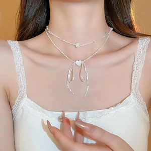 Detail of double-layer beaded necklace featuring a white heart pendant and bow tassel