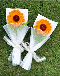 Handmade pipe cleaner sunflower bouquets wrapped in white tulle on green grass background