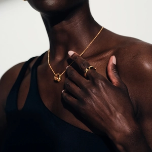 Detailed close-up of 18k gold plated stainless steel necklace and ring on a female model