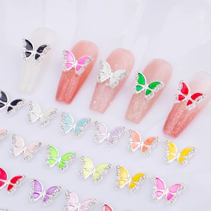 Macro detail of 3D alloy butterfly nail charms with oil drip wings and inlaid rhinestones
