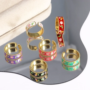 Macro detail of red enamel floral rings on a mirror surface with vintage gold finish