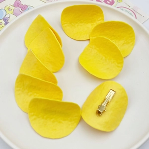 Detail of yellow potato chip hair clips with textured finish on white ceramic plate