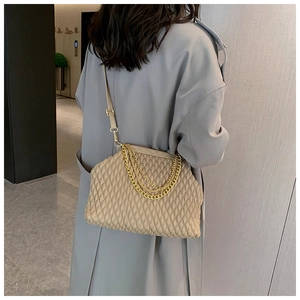 Detail view of beige quilted shoulder bag with decorative gold chain straps and PU leather