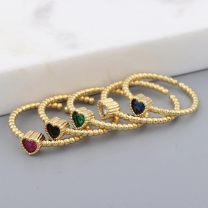 Set of five heart-shaped colorful zircon rings with gold beaded bands on marble