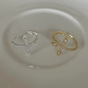 Close-up of gold and silver cross rings with zircon inlay on a ceramic display plate