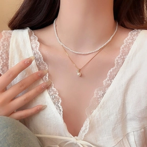 Close-up detail of a double-layered 18k gold plated necklace set with pearls and zircons