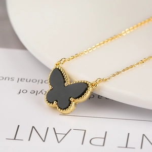 Macro shot of a black butterfly pendant with gold beaded edges on a delicate chain