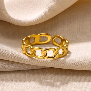 Macro detail of gold-plated stainless steel cuban chain ring on beige textured fabric