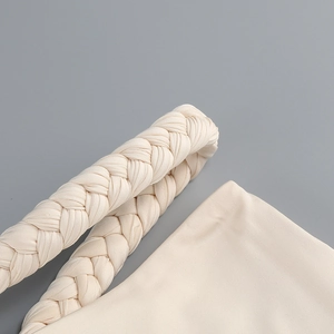 Close-up of the cream braided halter strap and fine ribbed knit texture of the dress