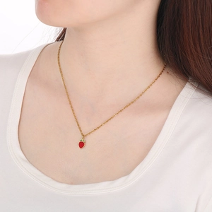 Close-up of a model wearing a gold strawberry pendant necklace with red enamel detail