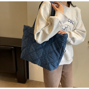 Grand sac cabas matelassé en denim bleu marine porté par un mannequin en mode décontracté