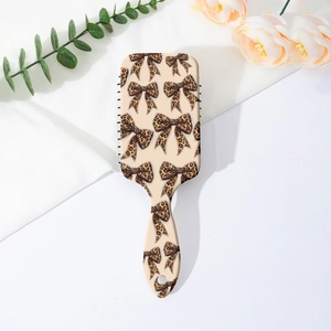 Detail view of air cushion hairbrush featuring a stylish leopard bow print on beige handle