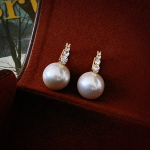 Vue macro de boucles d'oreilles dorées avec perles et zircons sur fond de velours