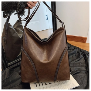 Detail of vintage brown leather bag with side zippers and smooth oil wax texture