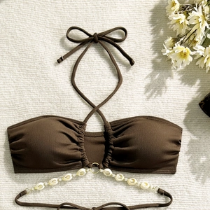 Close-up of ribbed brown bikini top featuring shell decor and halter neck ties
