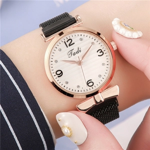 Close-up of Tadi rose gold watch with white wave dial and black mesh band on wrist