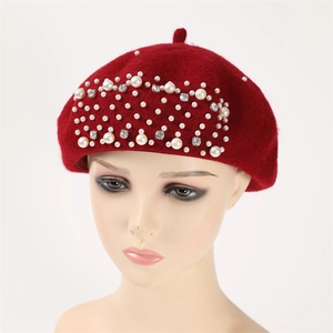 Detailed macro shot of deep red wool beret with white pearls and sparkling rhinestones