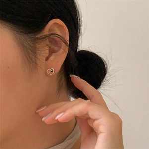 Close-up of minimalist black heart stud earrings in sterling silver worn by a model