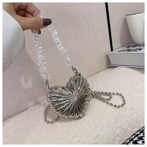 Detailed macro view of heart-shaped silver metal handbag with acrylic beads and chain