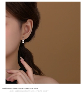 Macro shot of double pearl drop earrings featuring high-polish silver plating detail