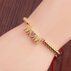 Close-up of gold MOM bracelet with pink crystal heart and red woven adjustable cord