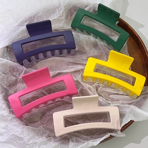 Rectangle hair claws set in purple, green, pink, and yellow colors on a wooden tray