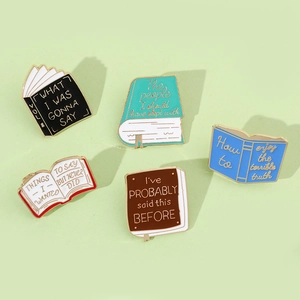 Macro view of five colorful enamel book pins with creative letterings and metal textures