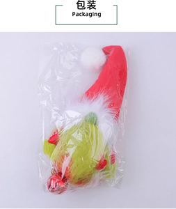 Detailed view of Grinch-style plush gnome with red Santa hat in clear packaging