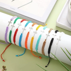 Pulseras tejidas a mano con cruz en varios colores sobre un soporte blanco