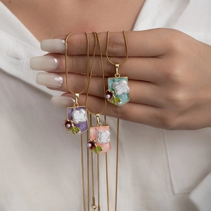 Detailed macro view of gold snake chain necklaces with pearls and floral oil painting charms