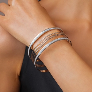 Close-up of multi-layer stacked bangles with hammered texture and glitter finish