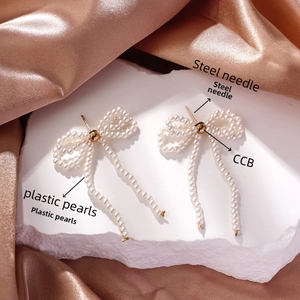Detail of bow-shaped pearl tassel earrings with steel needles on rose gold satin