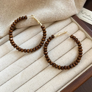 Détail de boucles d'oreilles vintage avec perles en bois brun et crochets dorés