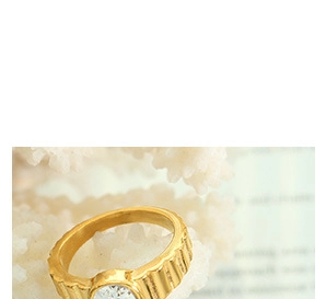 Macro shot of gold ribbed band ring with a round clear zircon set on a white coral base