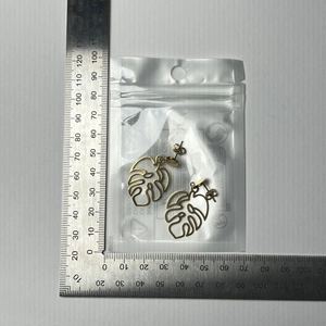 Size measurement of golden hollow monstera leaf earrings showing 38mm length with a ruler