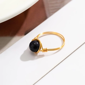 Macro detail of handmade wire-wrapped ring featuring a sparkling blue sandstone bead