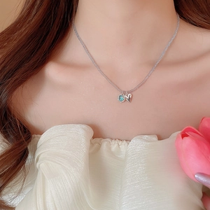 Close-up of a double heart necklace with blue crystal and silver pendant on a beaded chain