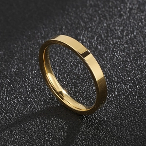 Detailed macro shot of a 3mm polished gold stainless steel band ring on black texture