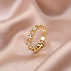 Gold open ring with hollow hearts and rectangular zircon crystals on satin fabric
