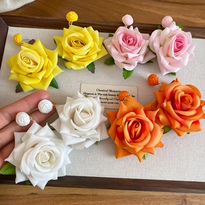 Detail of floral fabric earrings set in pink, yellow, orange and white silk petals