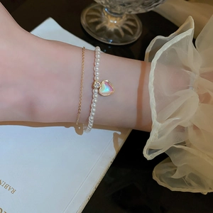 Close-up of a double-layer gold-plated bracelet with pearls and a colorful heart pendant