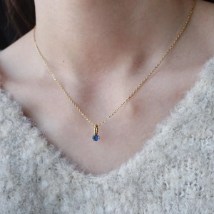 Primo piano della collana in titanio dorato con ciondolo in pietra blu su modella