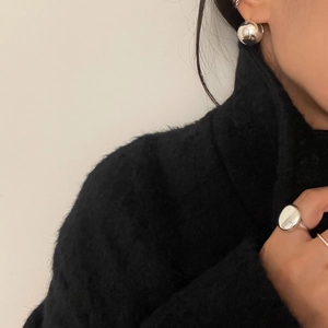 Close-up of minimalist polished sterling silver ring and spherical stud earrings on a model