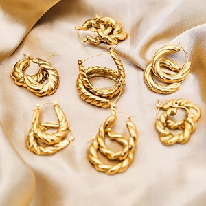 Detailed macro shot of gold plated stainless steel twisted hoop earrings on silk