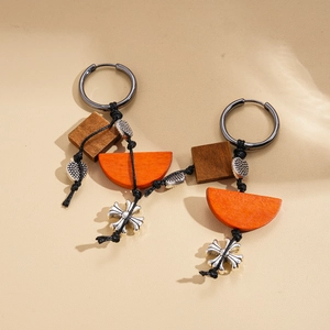 Ethnic retro wooden earrings with silver cross pendant on beige leather background