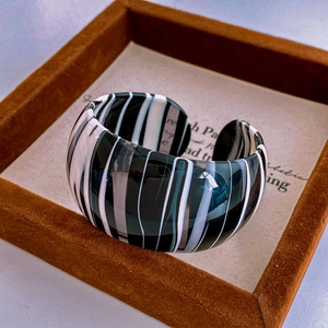 Detailed view of wide open cuff bracelet featuring black and white vintage wood grain texture