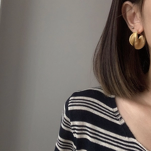 Textured gold leaf earrings with irregular layered design on model with striped shirt